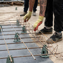 Builder in action, placing continuous wire high chair spacers on reinforcement mesh for concrete support.