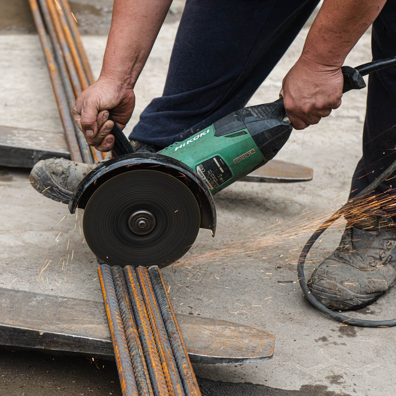 Close-up of a disc saw slicing through steel rebars.