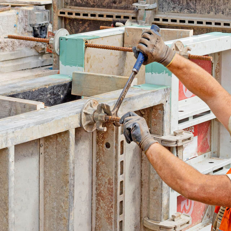 Construction worker installing formwork tie bars in a building project