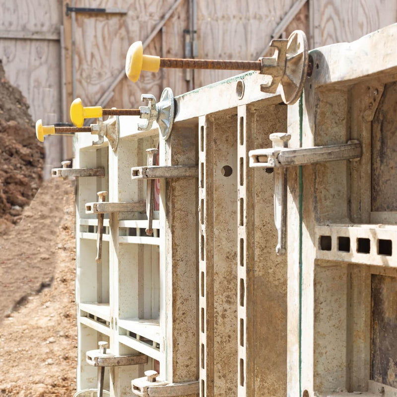 Formwork tie bar installation with protective caps in place on a construction site